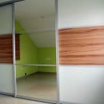 moderner Schiebetürenschrank in weiß mit kernigem Holz kombiniert und großer Spiegeltüre in der Mitte